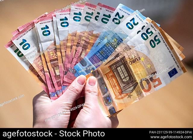 ILLUSTRATION - 24 November 2023, Berlin: A person holds numerous euro banknotes in his hand. Photo: Hannes P. Albert/dpa. - Berlin/Berlin/Germany