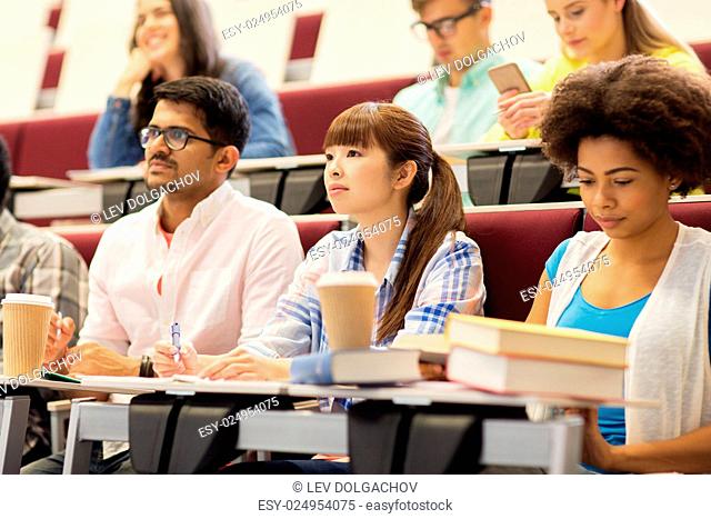 education, high school, university, learning and people concept - group of international students with notebooks and coffee in lecture hall