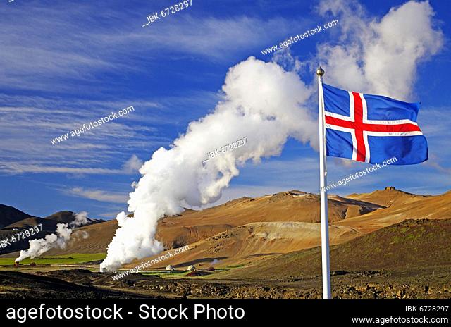 Icelandic flag in front of hot steam plumes, geothermal fields in the background, Reykjahlíð, Myvatn, Iceland, Europe
