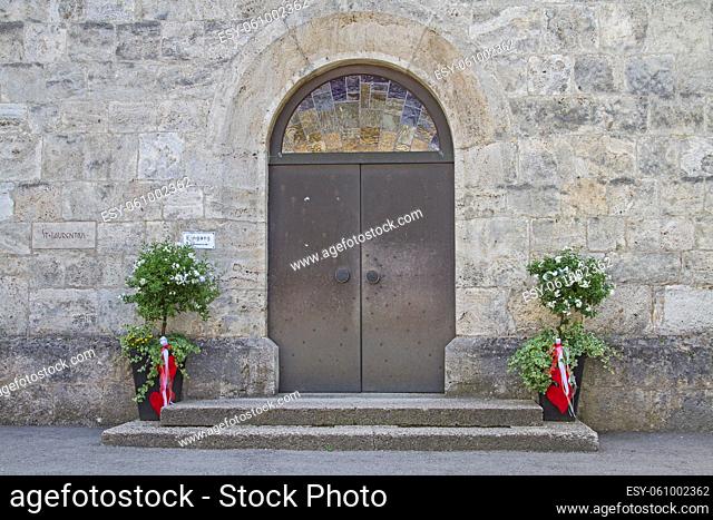 Mit Pflanzentöpfen festlich geschmückte Tür einer Dorfkirche in Oberbayern