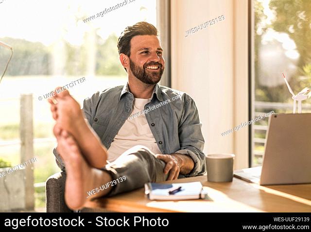 Happy businessman sitting at desk in home office