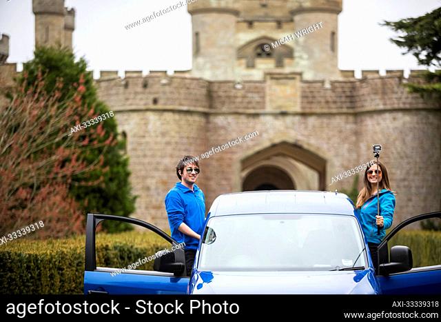 Couple traveling in camper van stop for a selfie in front of Eastnor Castle in Ledbury; Eastnor, Herefordshire, England, UK