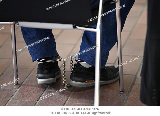 16 October 2018, Baden-Wuerttemberg, Konstanz Am Bodensee: One of the defendants is sitting on his chair in the courtroom with ankle cuffs