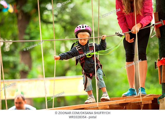 Kids on obstacle course in adventure park in mountain helmet and safety equipment