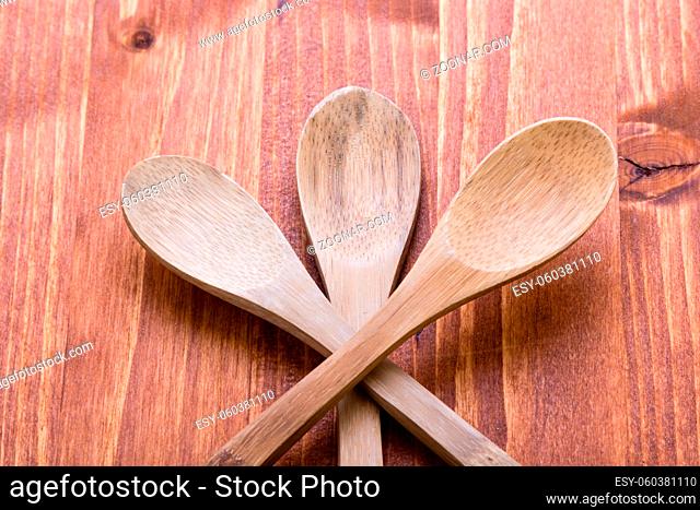 three brown wooden spoons on wooden table