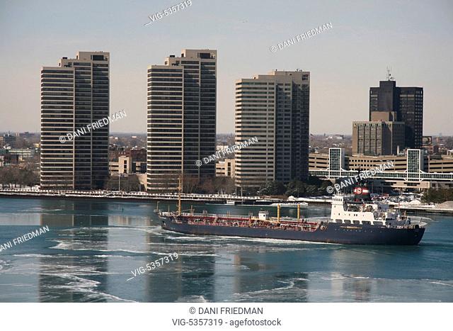 A bulk carrier ship travels along the Detroit River and passes apartment buildings in Detroit, Michigan, USA. The ship carries dry bulk cargo such as iron ore