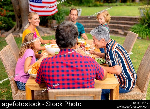 Caucasian three generation family sitting at table eating meal in the garden