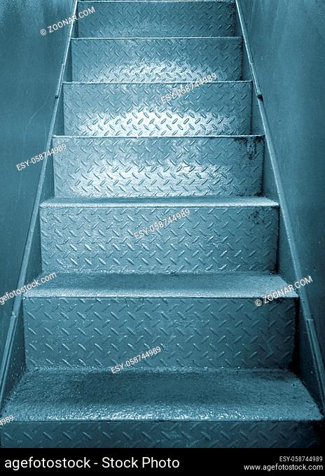 grey steel industrial staircase with rough patterned grip texture in a passage between two metal plate walls