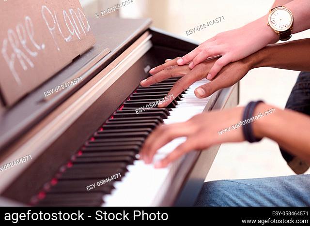 Picture of man playing piano while lady explaining him something. Professional musician playing outdoors. Closeup of keyboard of piano