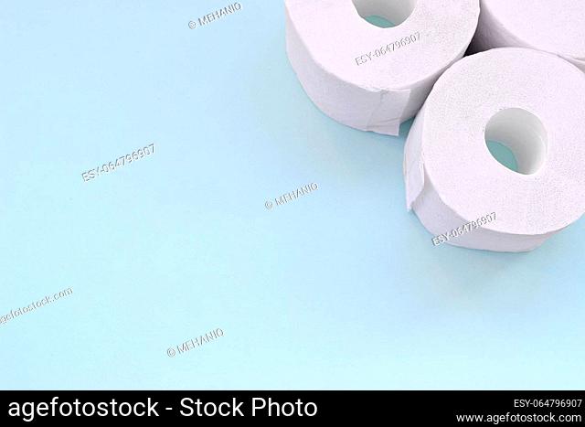 Coronavirus pandemic panic shopping concept. Few new toilet paper rolls on light blue background. Minimalistic flat lay composition with copy space for text