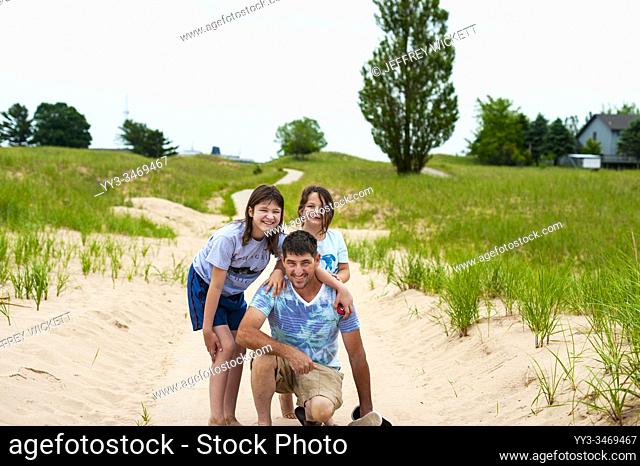 Father and daughers posing on dunes trail in Ludington, Michigan, USA.