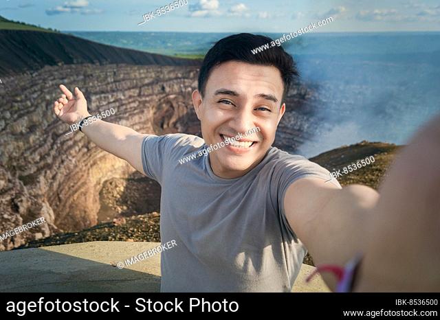 Turista haciéndose un selfie en un mirador. Guapo turista tomando un selfie de vacaciones. Hombre aventurero haciéndose un selfie en un mirador