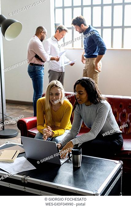 Business team using laptop and discussing documents in loft office