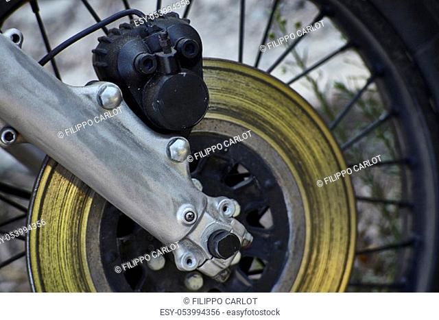 Detail of a disc brake with caliper and fork mounted on a spoked wheel of a vintage motorcycle