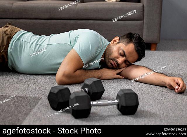 Portrait of tired young man lying down on floor during exercise