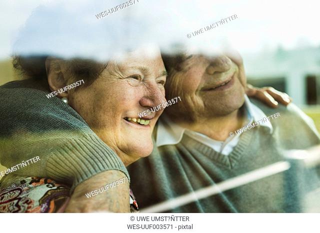 Happy senior couple head to head looking through window