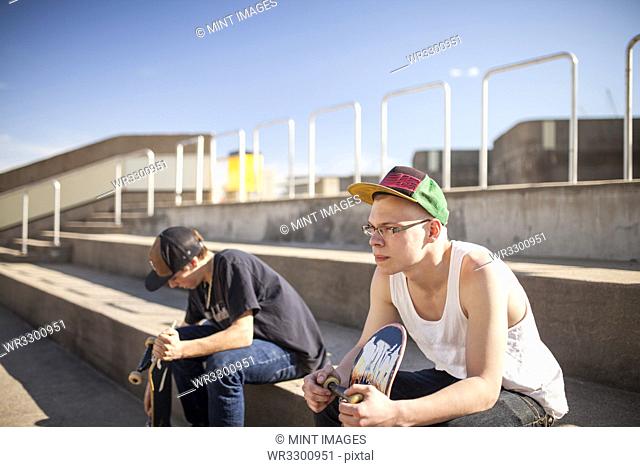Caucasian men with skateboards sitting on steps