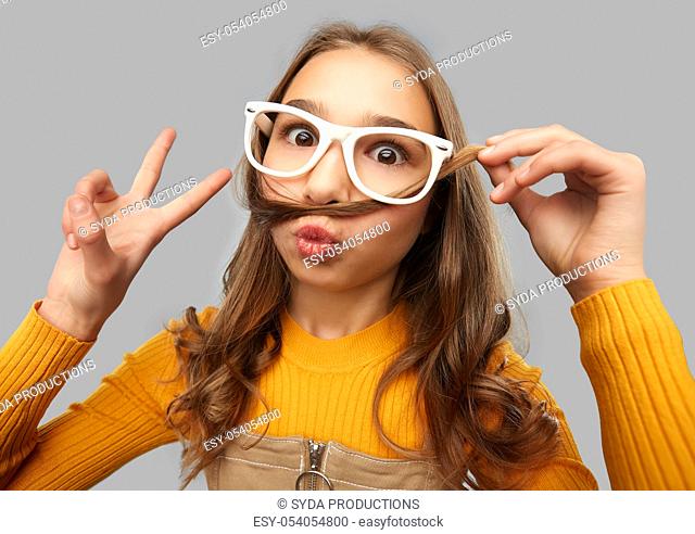 teen girl in glasses makes faces and shows peace