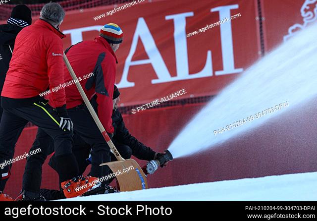 04 February 2021, Bavaria, Garmisch-Partenkirchen: Alpine skiing: World Cup, downhill, men: Helpers prepare the Kandahar downhill with water to freeze the snow