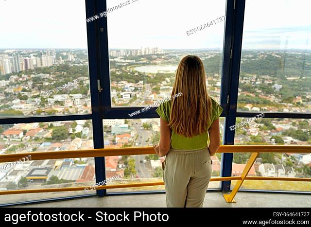 Back view of young woman looking Curitiba cityscape from Torre Panoramica the panoramic tower of Curitiba, Parana, Brazil