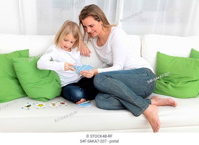Mother and daughter playing cards on couch