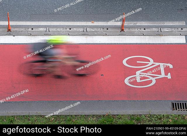 31 August 2021, Hessen, Frankfurt/Main: A cyclist rides in a bicycle lane along a road. (Wiping effect by long exposure) Several associations present a petition...