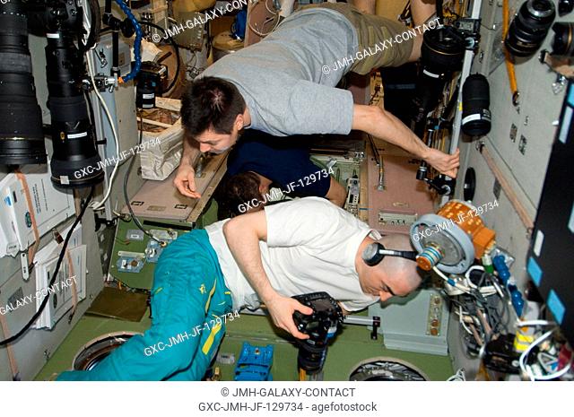 From windows in the International Space Station's Zvezda Service Module, Russian cosmonauts Oleg Kononenko (top), Anatoly Ivanishin (foreground) and Anton...