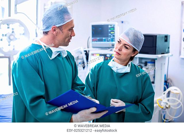 Surgeons discussing over medical reports in operation room