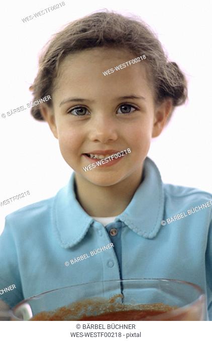 Girl (4-7) holding bowl of tomato sauce, close-up, portrait