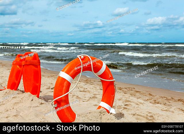 A red lifeguard stuck in the sand on the beach