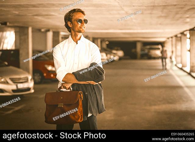 Young Hipster Guy In Sunglasses Stands In The Parking Lot. The Office Worker Went Out For Lunch. Business Concept Photo