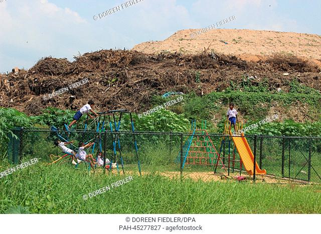 Children play on the playground of a primary school in front of the trash mountain in the district Kolonnawa is pictured in Colombo, Sri Lanka, 18 November 2013
