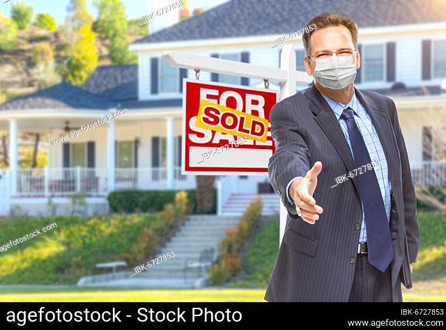 Male real estate agent reaching for hand shake wearing medical face mask with sold for sale sign behind
