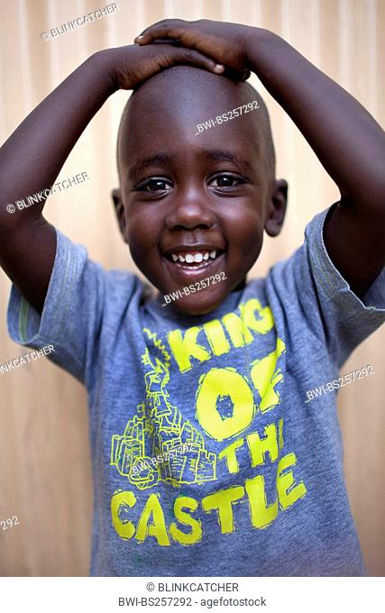portrait of a little boy happily presenting his T-shirt with the wrighting 'King of the Castle', Burundi, Bujumbura Mairie, Bujumbura