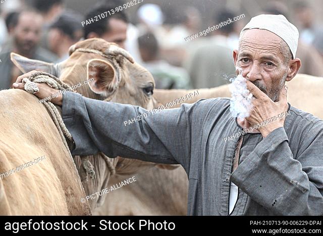 13 July 2021, Egypt, Ashmoun: A man smokes a cigarette at Shama livestock market ahead of the Muslim's holiday of Eid al-Adha