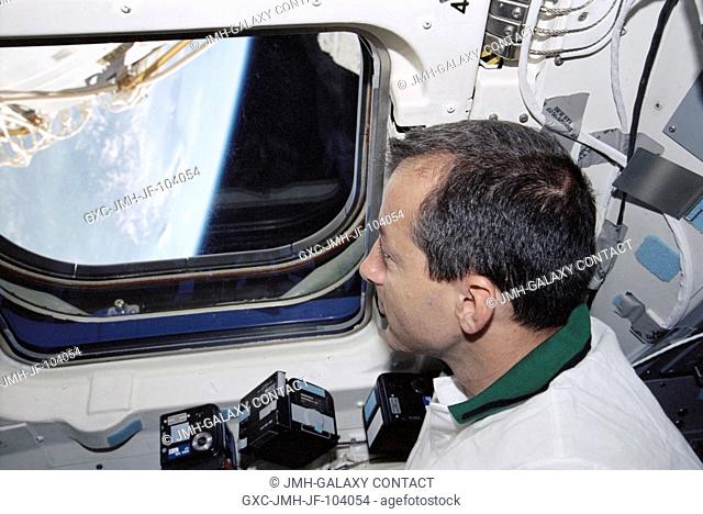 Astronaut Philippe Perrin, STS-111 mission specialist representing CNES, the French Space Agency, looks out an aft flight deck window of the Space Shuttle...