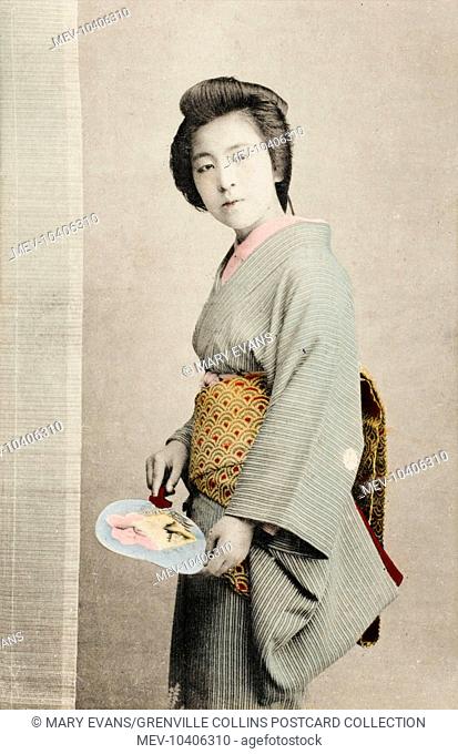 A Japanese Geisha girl, places her seal on a hand-painted fan