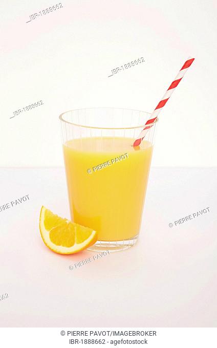 Fresh orange juice with a straw and orange