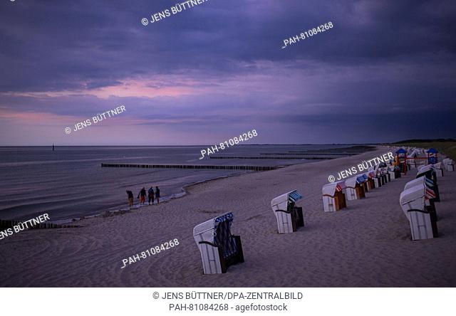 Vacationers walk at the beach during sunset at the Baltic Sea spa town Graal-Mueritz, Germany, 09 June 2016. | usage worldwide