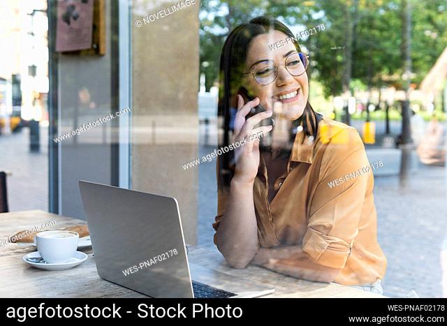 Smiling female professional talking on smart phone in cafe