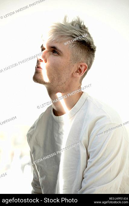 Man with beam of light on face sitting against white background