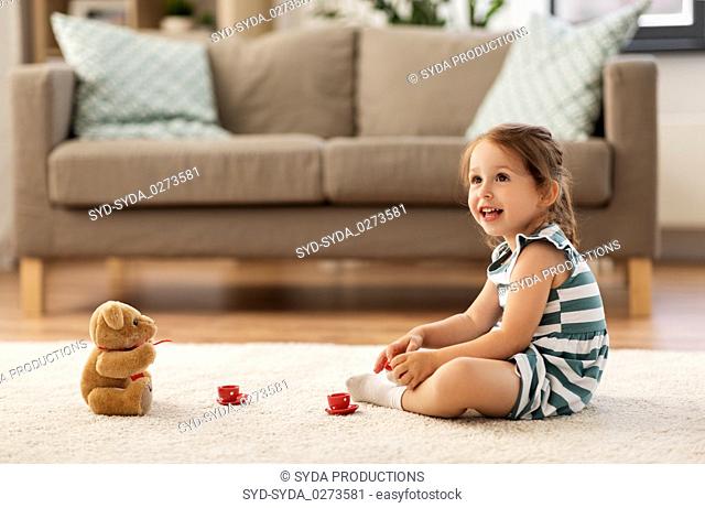 little girl playing with toy tea set at home