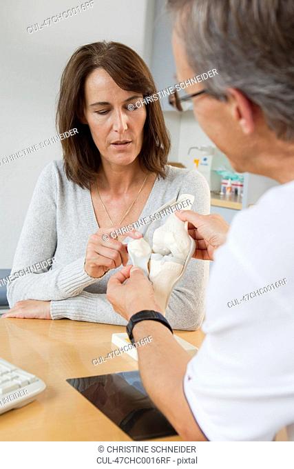 Doctor showing patient model of bones