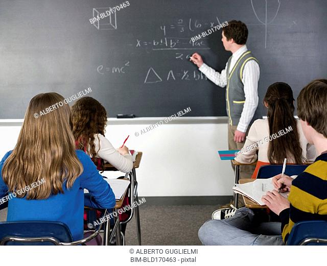 Teacher writing on chalkboard in classroom