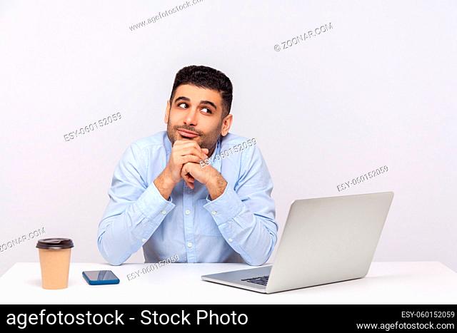 Optimistic happy businessman sitting office workplace with laptop on desk, leaning on hands while dreaming, making wish, musing thinking inspired