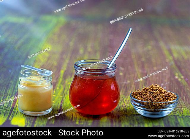 Honey, pollen and royal jelly in glass containers placed on an old board