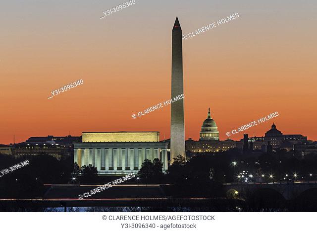 The Lincoln Memorial, Washington Monument, and US Capitol building set against an orange sky during morning twilight in Washington, DC