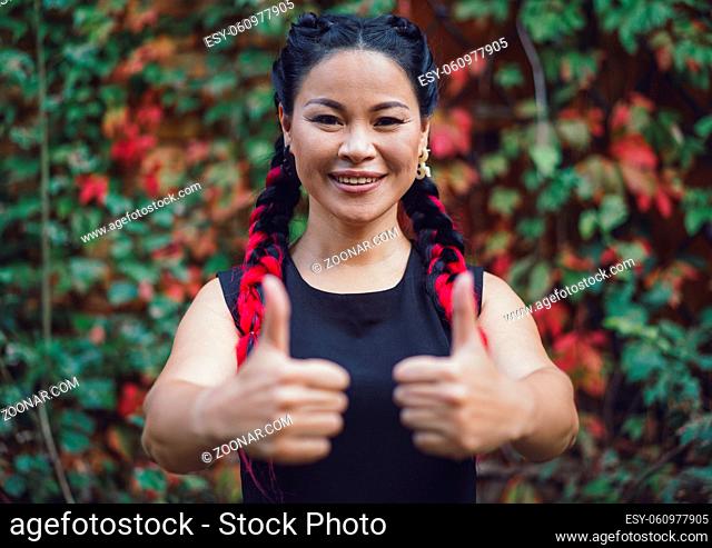 Close-up Thombs Up by Asian Female Model Outdoor. Beautiful Middle-Aged Asian Showing Thumbs Up and Smiling Happily