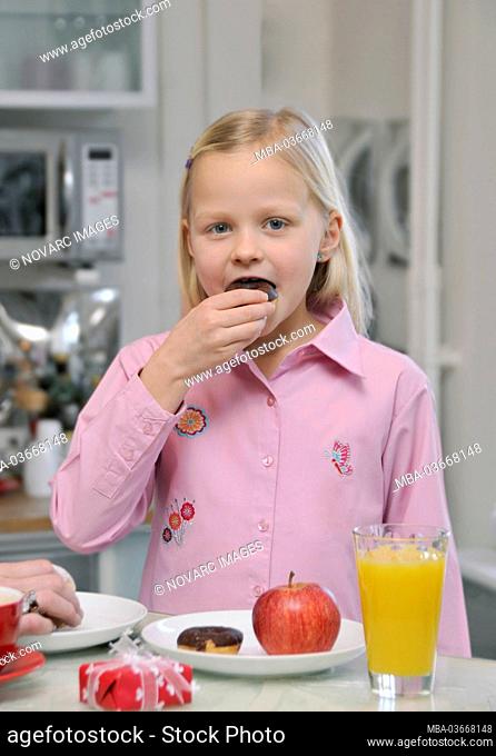 Young girl eats chocolate and fruits at the table