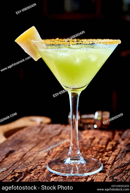 Green margarita melon cocktail with copy space on wooden background